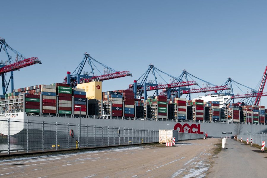 A container ship docked at a bustling shipping terminal in Hamburg, Germany.